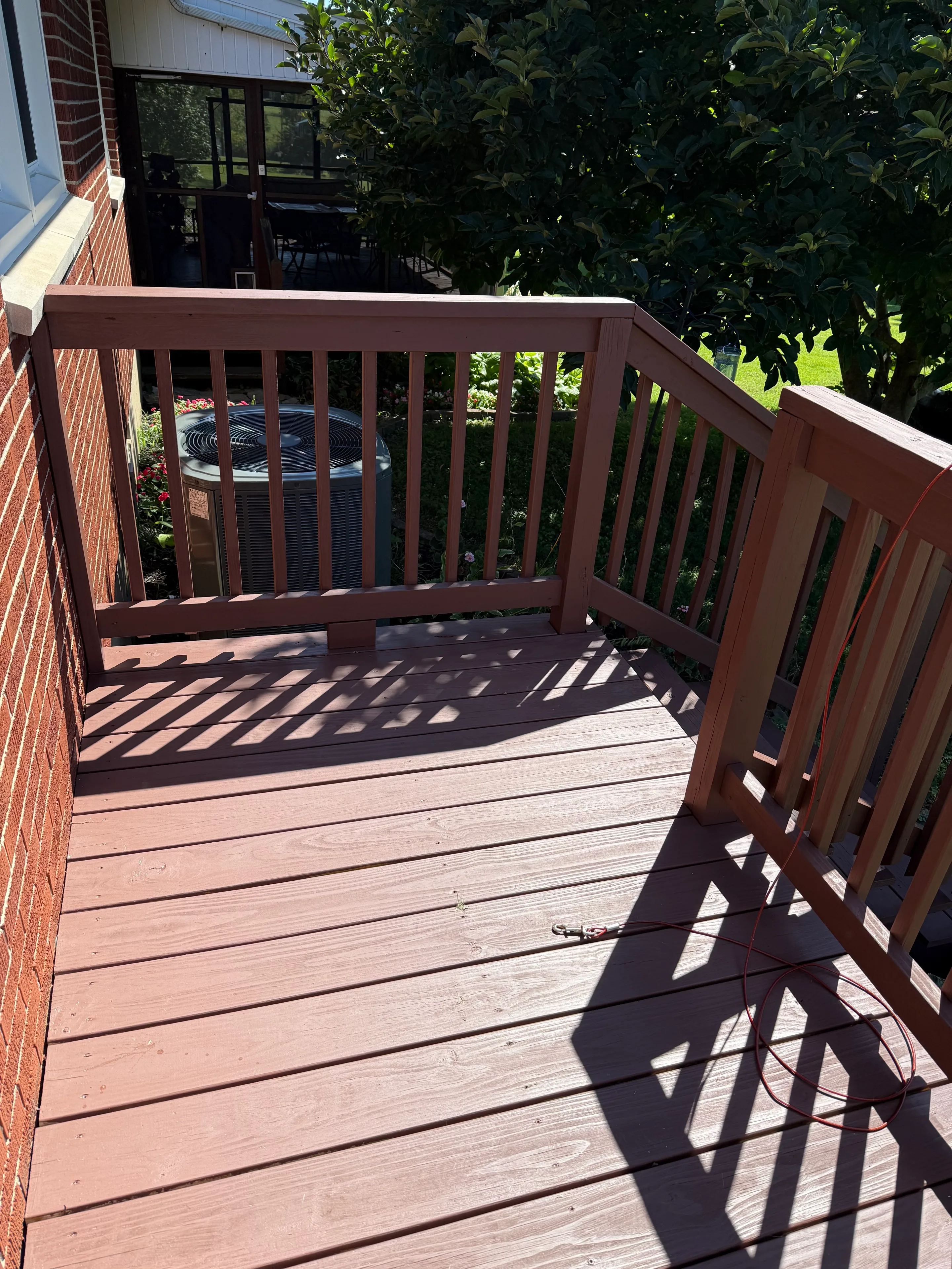 Finished deck landing and railing beside a brick home