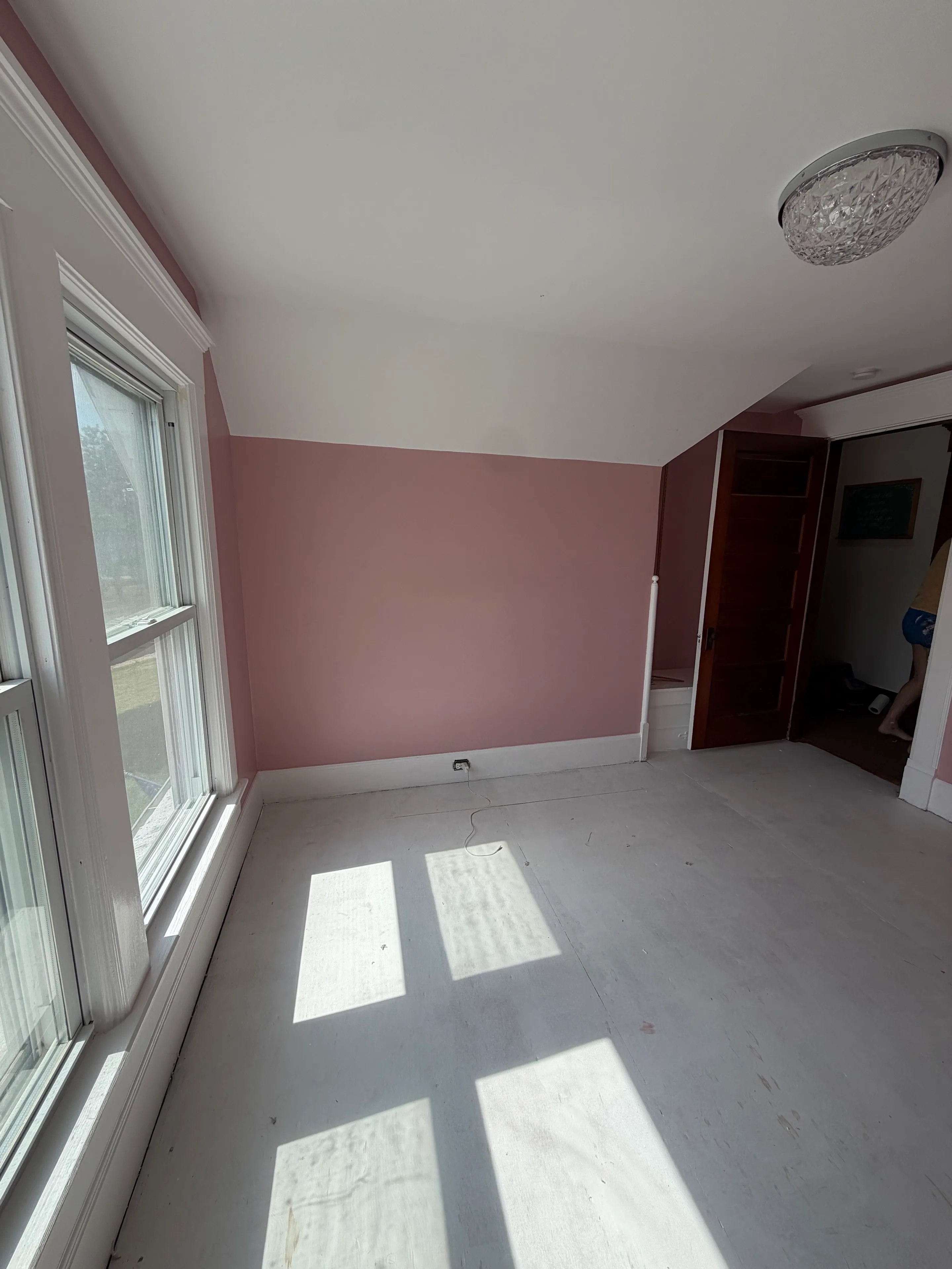 Finished soft-rose room with white ceiling, trim, and sunlit windows