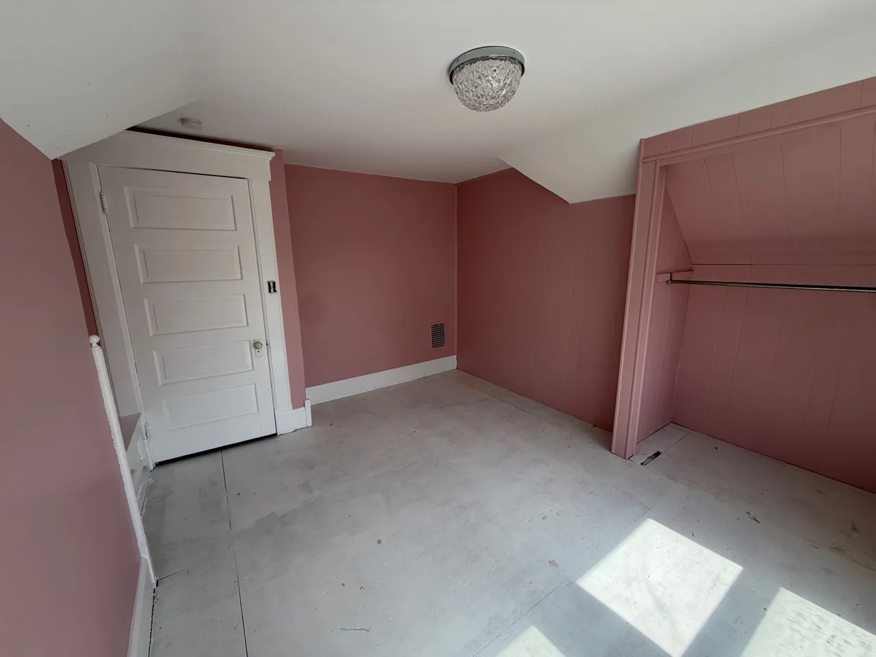 Finished soft-rose room showing the painted paneled wall and closet alcove