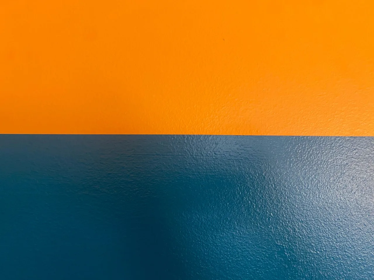 Close detail of the clean line between golden-orange and deep teal paint
